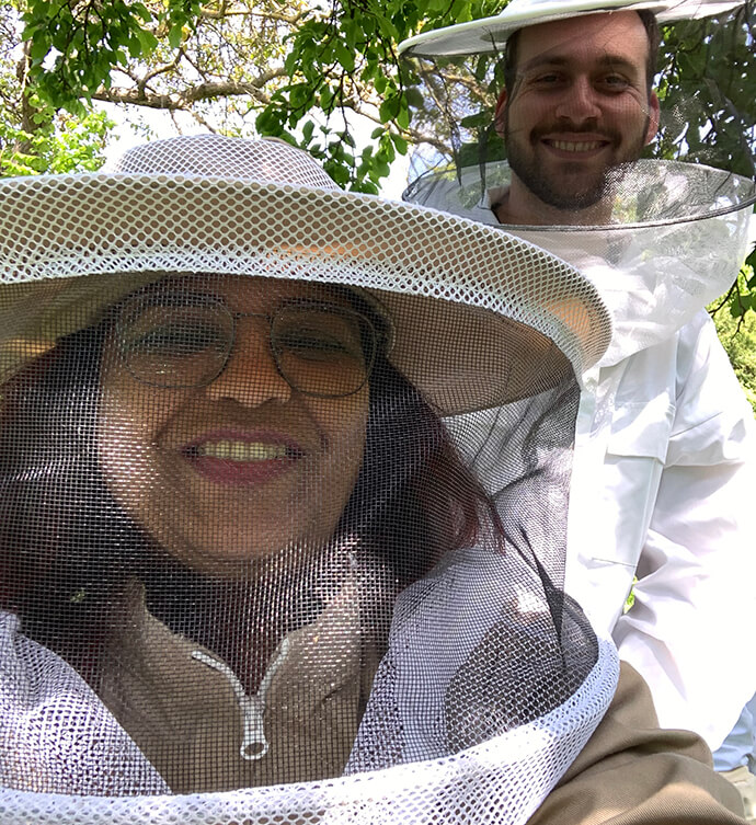 Eine Mitarbeiterin von IT-Kompass trägt Schutzkleidung, um sich um die Bienen zu kümmern.