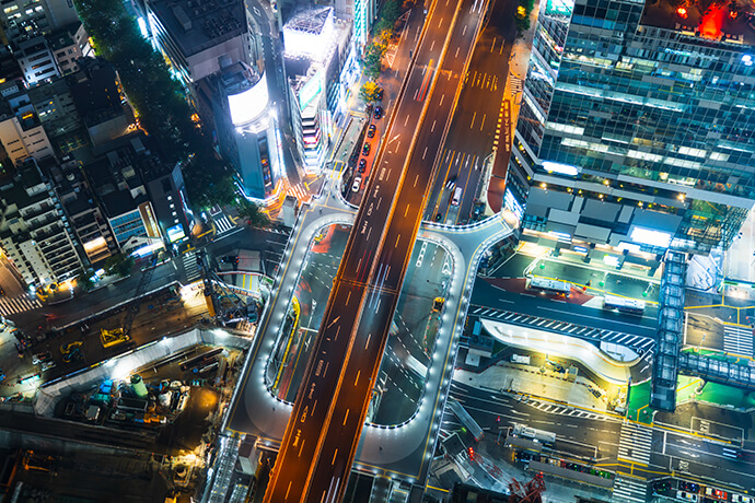Tokio von oben in der Nacht. Die Straßen, Gebäude und Baustellen leuchten hell.