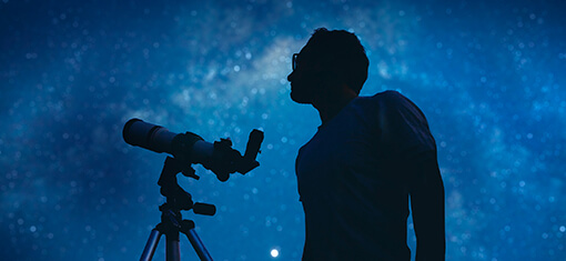Astronom mit einem Teleskop, der die Sterne und den Mond beobachtet.