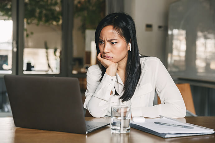 Eine Frau blickt konzentriert auf einen vor ihr befindlichen Laptop.