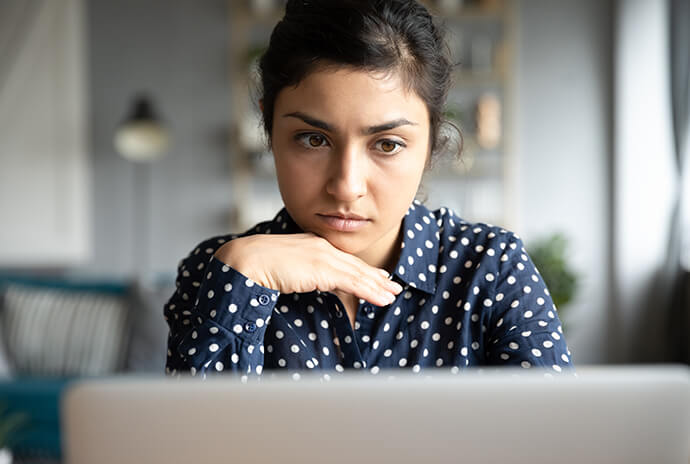 Eine junge Frau sitzt vor ihrem Rechner und prüft mit ihrem neugewonnenen Wissen, ob eine E-Mail vertrauenswürdig ist.